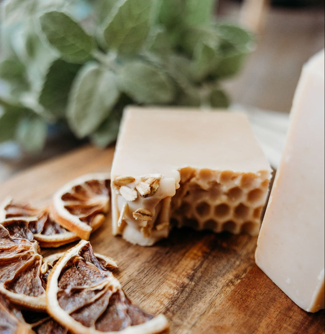 Honey oat milk soap with honeycomb pattern and dried citrus slices on a wooden board.