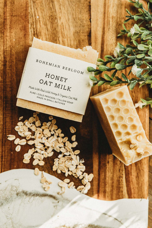 Bar of soap with a label on a wooden surface with oats and greenery