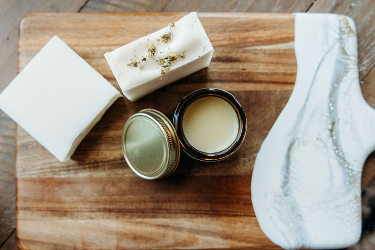 Two pieces of chamomile soap with an open container of herbal tallow balm.