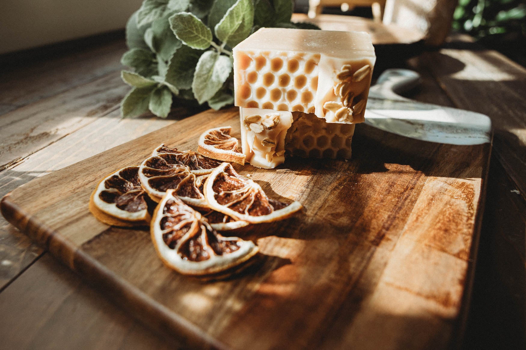 Wooden cutting board with dried citrus slices and a honeycomb-shaped soap bar on a wooden surface.