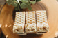 Three square honey oat milk bars on a wooden surface