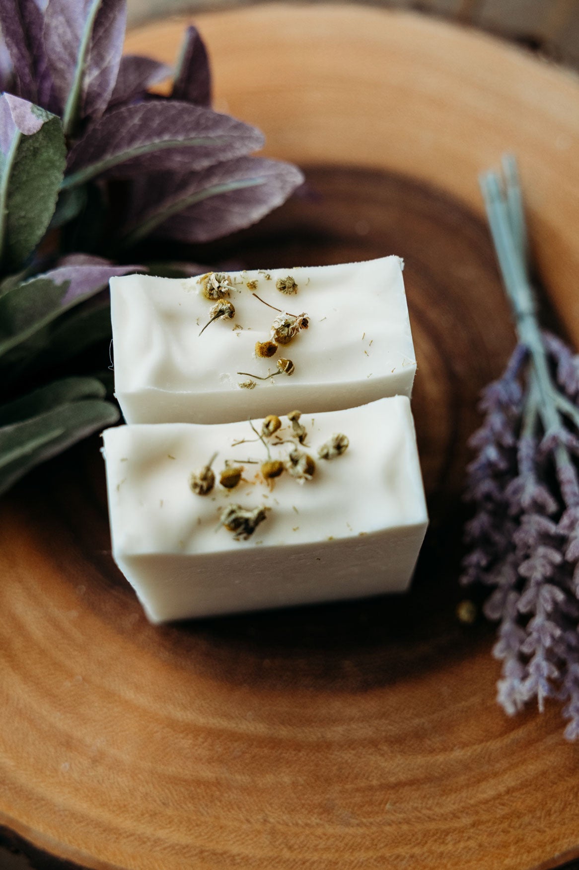 Two bars of chamomile lavender soap with Bohemian Rebloom label on a wooden board with dried lavender flowers.