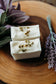Two bars of chamomile lavender soap with Bohemian Rebloom label on a wooden board with dried lavender flowers.