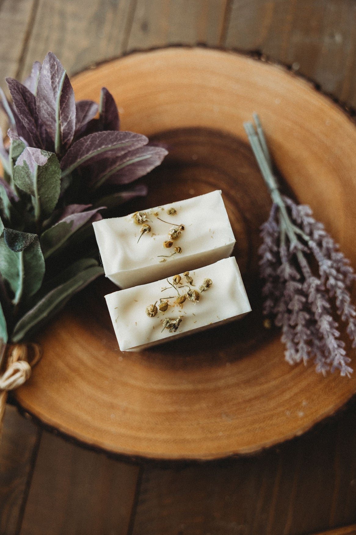 Two bars of chamomile lavender soap with Bohemian Rebloom label on a wooden board with dried lavender flowers.