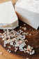 Two pieces of himalayan sea salt soap on a wooden surface with small bath salts.