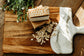 Bar of soap on a wooden cutting board with a white scrub brush and oats