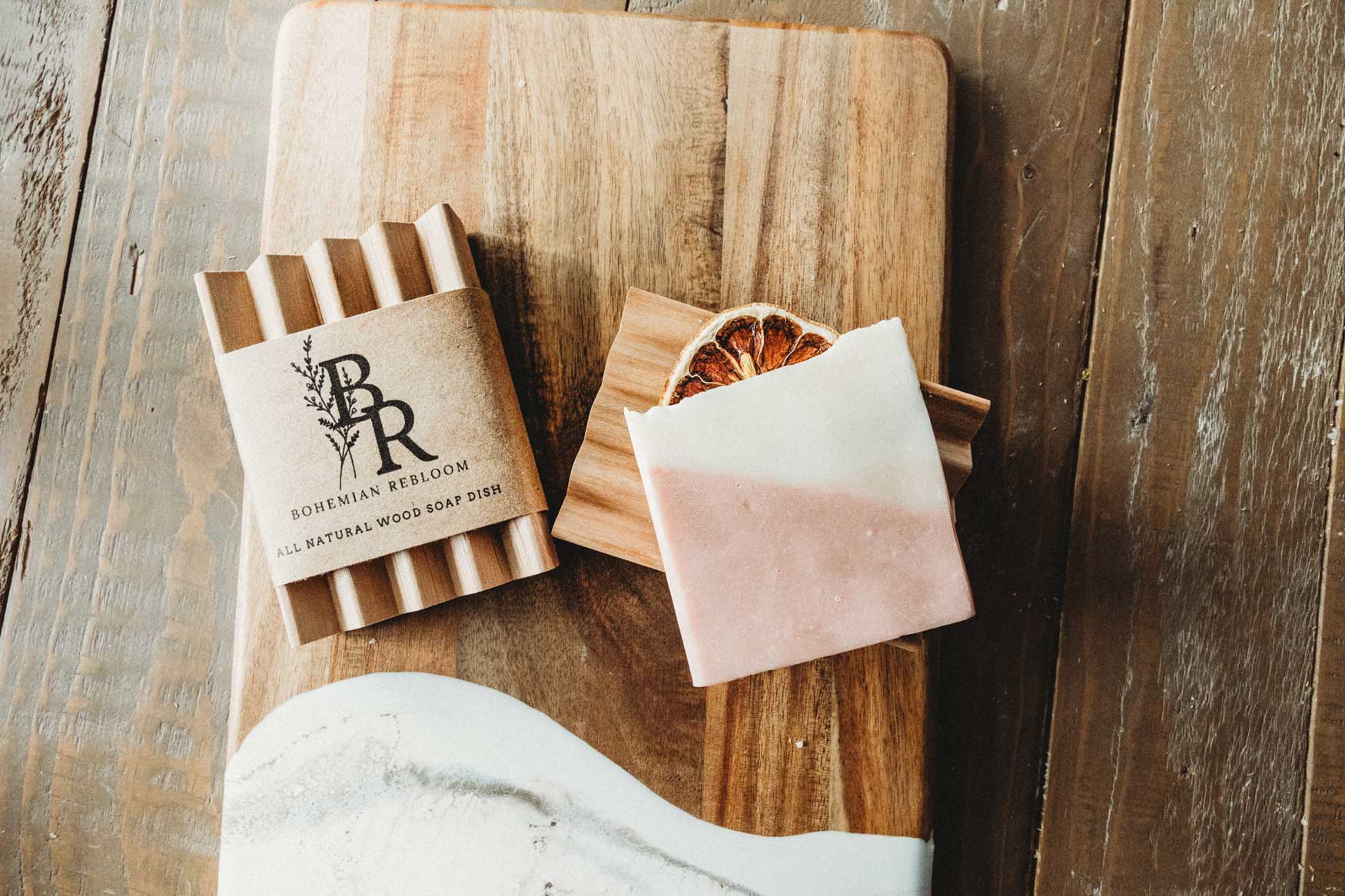 Wooden soap dish with Bohemian Rebloom label and a bar of soap on a wooden surface