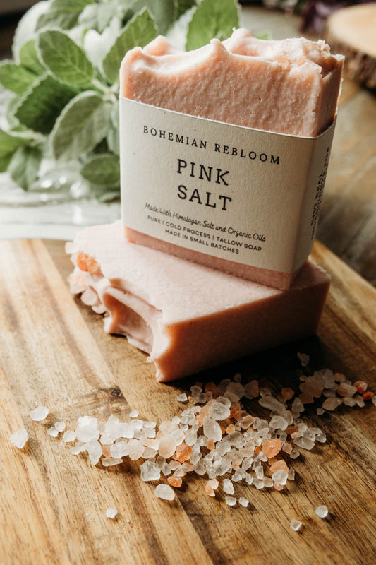 Bar of soap with 'Bohemian ReBloom' packaging on a wooden surface with himalayan salt crystals.