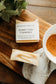 Bar of honey chai turmeric soap with 'Bohemian Rebloom' label on a wooden board with a cup of tea and leaves.