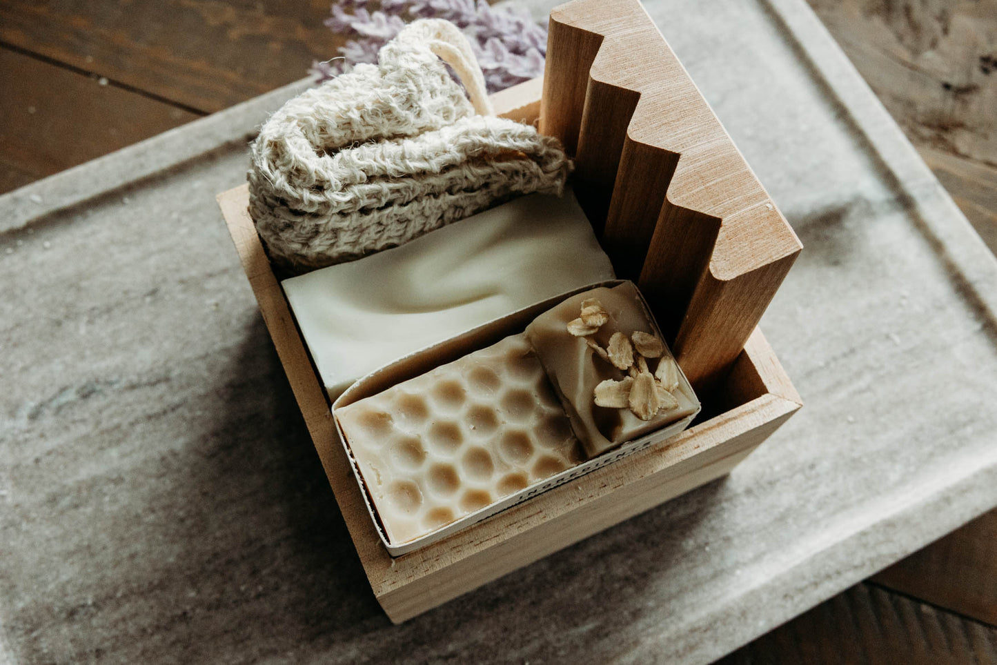 Two soaps with different textures in a wooden box on a textured surface