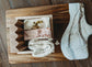Wooden tray with two bars of soap, a soap saver, and a wooden soap dish on top of a wooden surface.