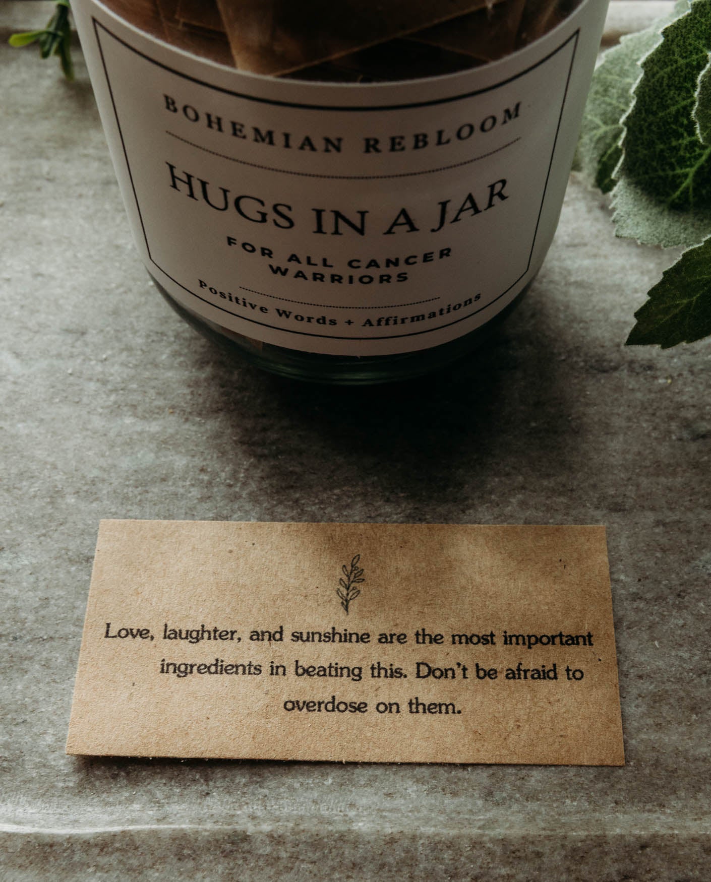 Candle labeled 'Hugs in a Jar' by Bohemian Rebloom with a quote on a textured surface.