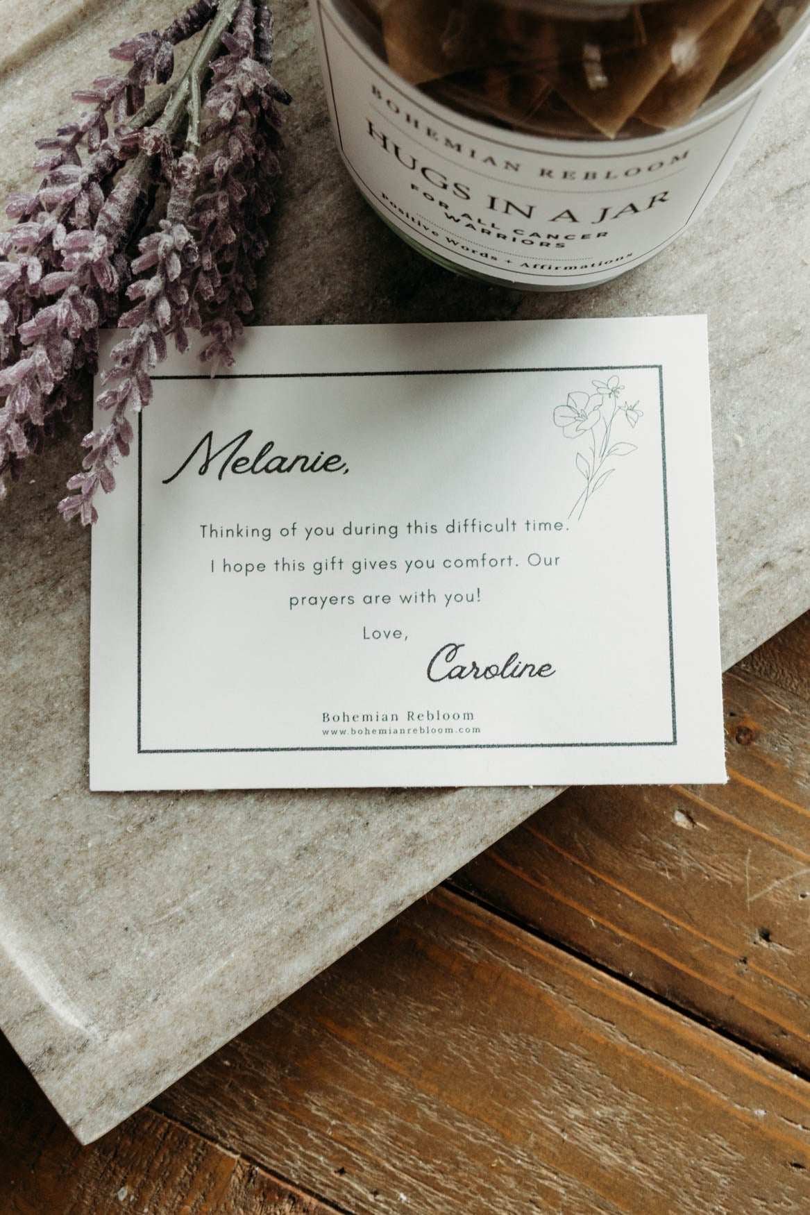 Card with personalized message next to a jar of 'Hugs in a Jar' on a wooden surface