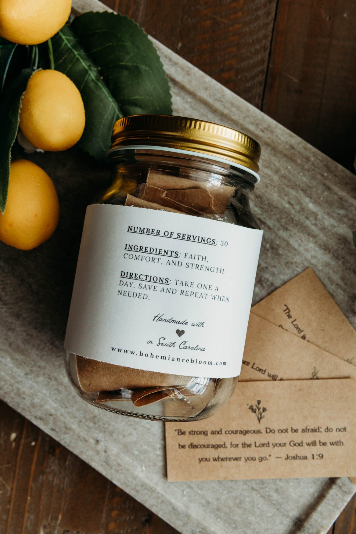 Jar with a label on a wooden surface with lemons and an cards with inspirational Bible versus and scriptures.