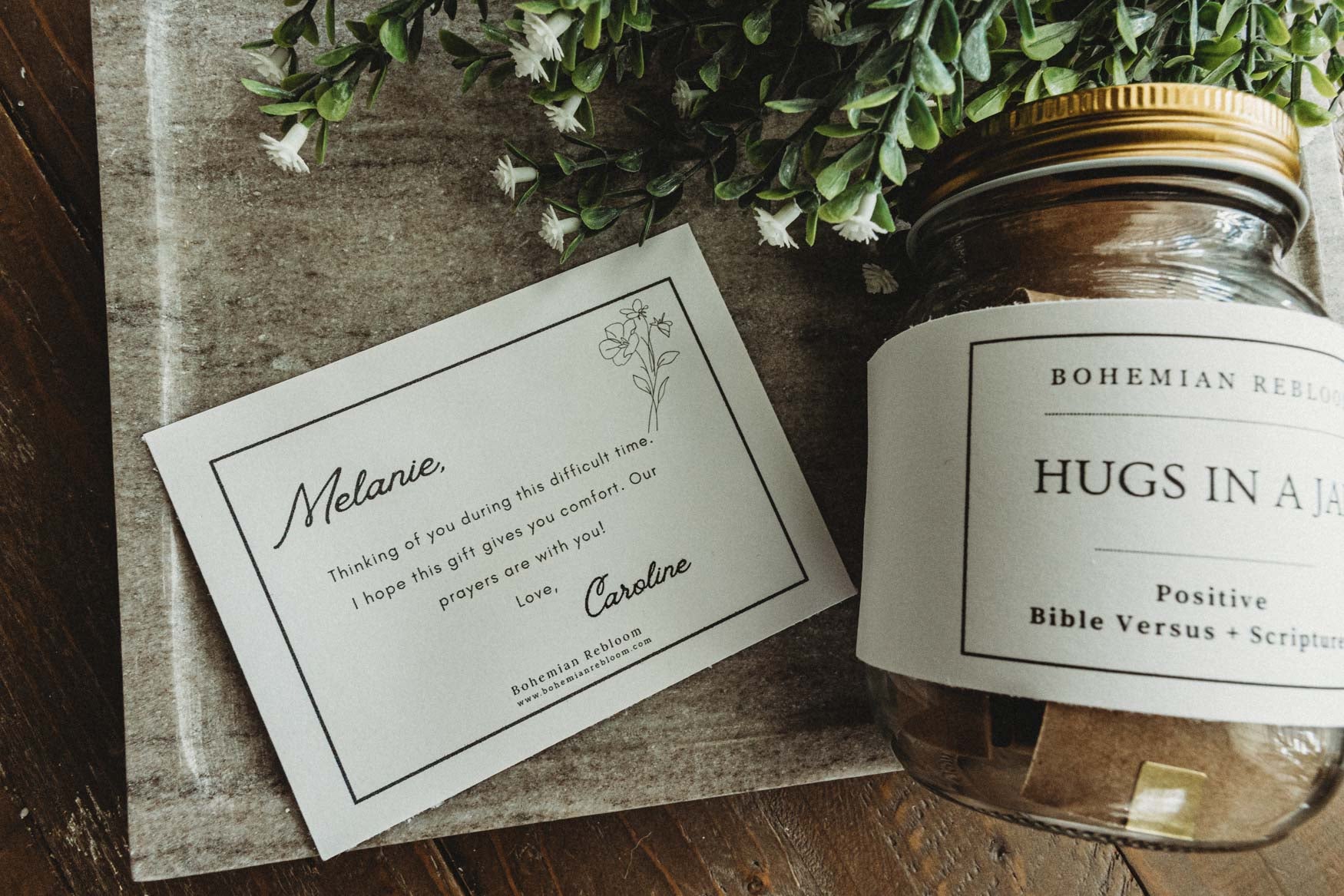 Jar labeled 'Hugs in A Jar' with a personalized card on a wooden surface with a gift note message.