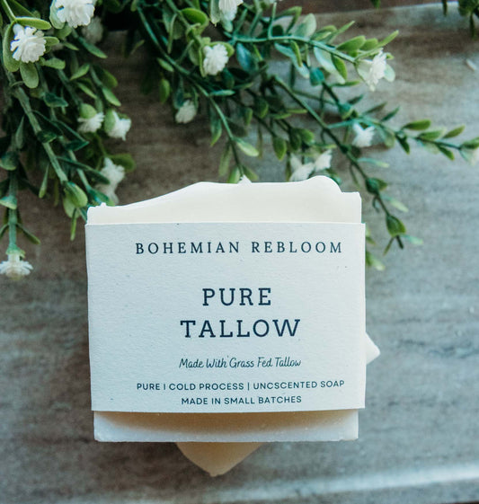 Bar of soap with 'Bohemian Rebloom' Pure Tallow Soap label on a stone surface with greenery.