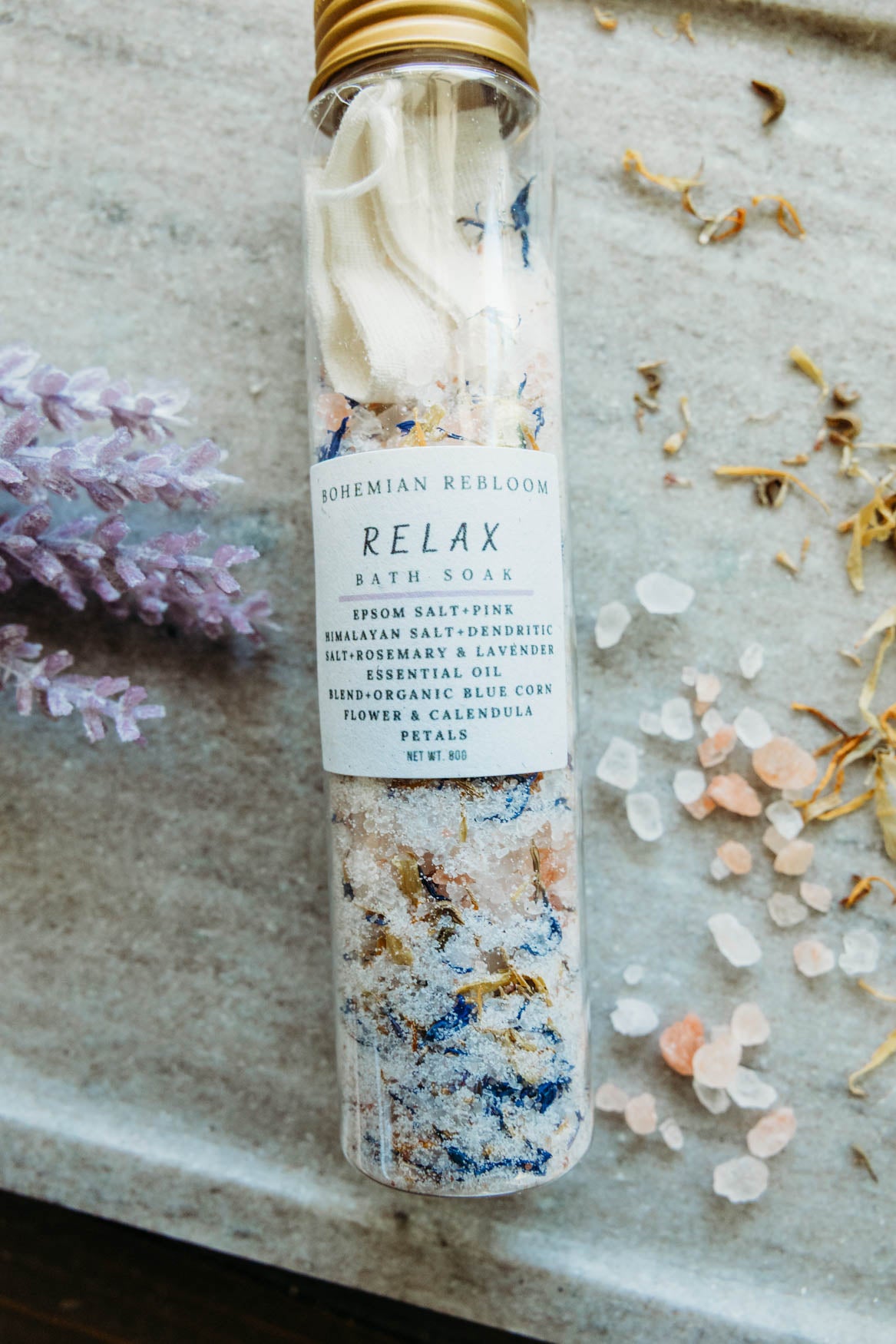 Bath salt test tube labeled Relax with floral and salt on top of marble cutting board.