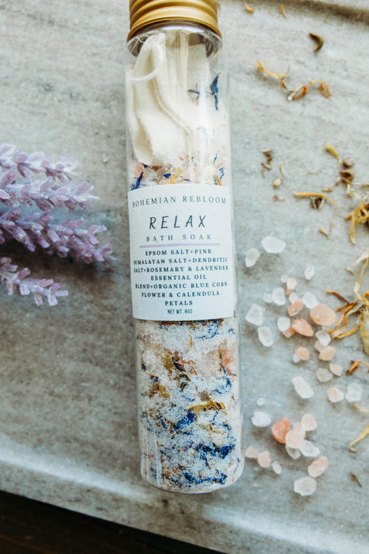 Bath salt test tube labeled Relax with floral and salt on top of marble cutting board.