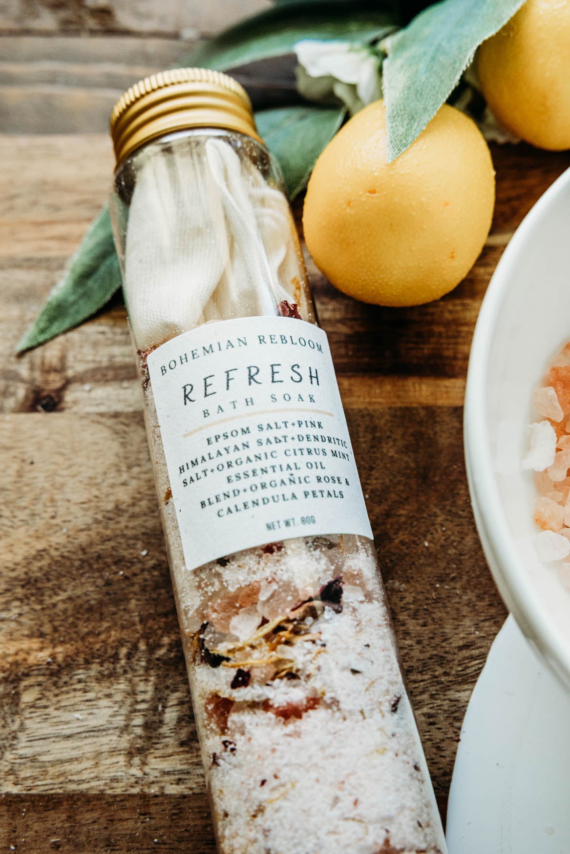Bottle of Bohemian Republic bath salts on a wooden surface with lemons and a bowl.
