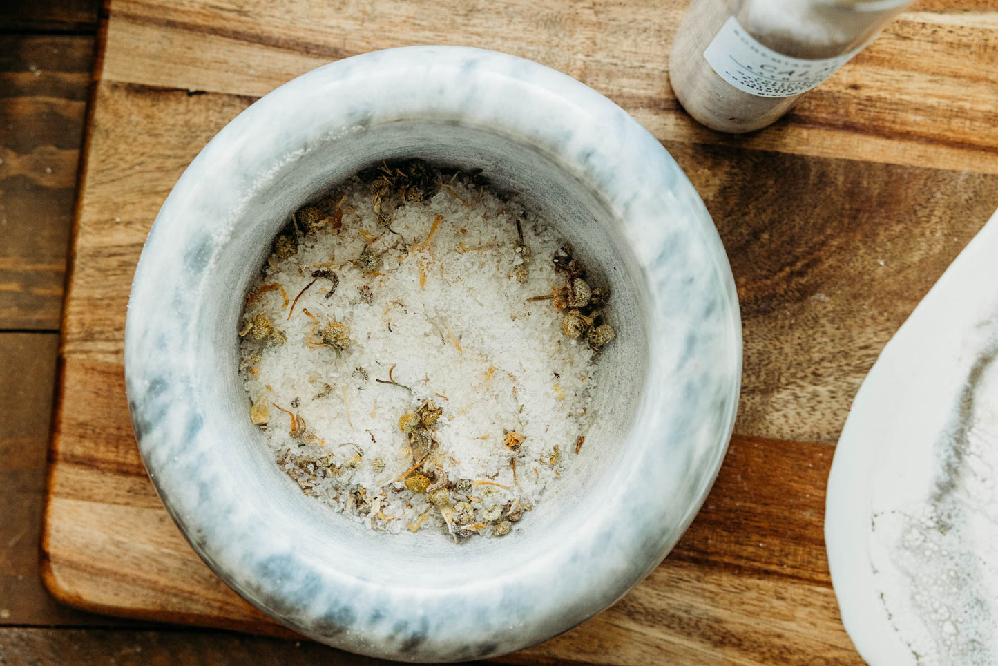 Mortar and pestle on a wooden surface with bath salts inside.