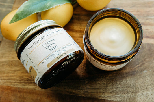 Two jars of Bohemian Rebloom Citrus Tallow balm on a wooden surface with lemons in the background.